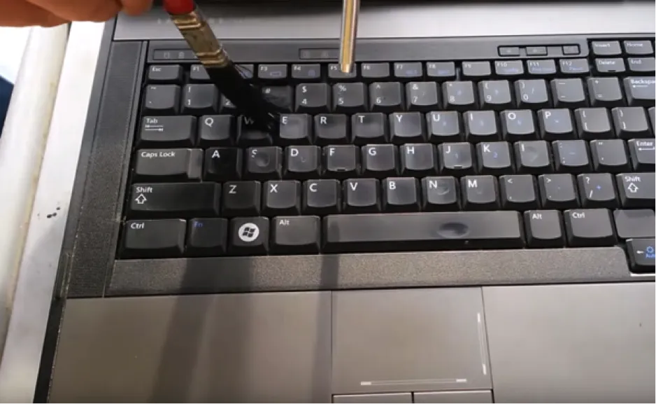 Lật úp laptop và dùng bình xịt khí nén làm sạch bụi bẩn từ bàn phím