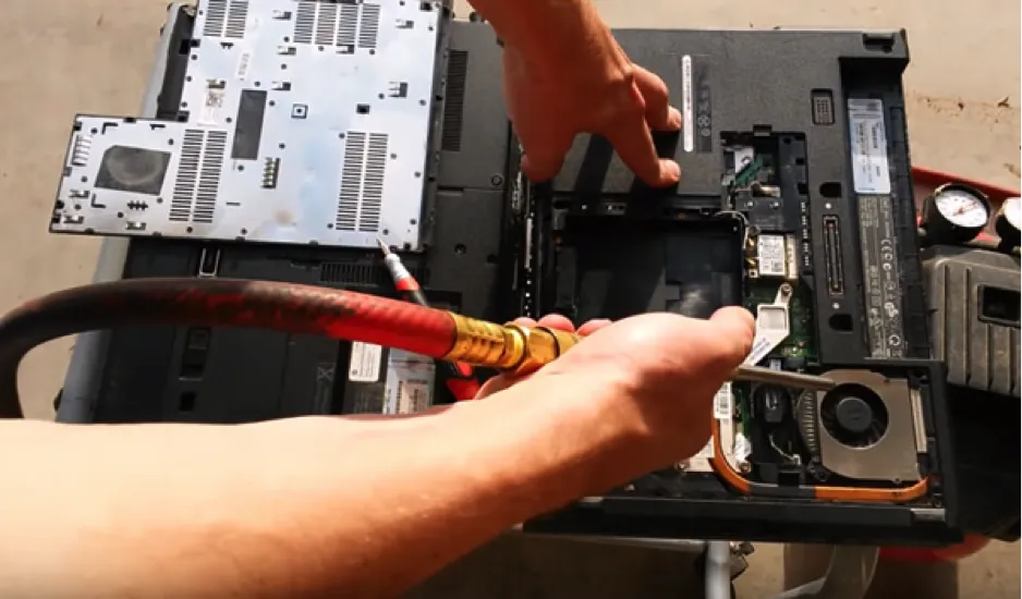 Kỹ thuật viên đang tháo nắp lưng laptop để tiến hành vệ sinh bên trong