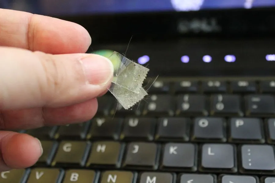 Sử dụng băng keo dính để lấy đi các mẩu vụn và tóc bám trên bề mặt bàn phím.