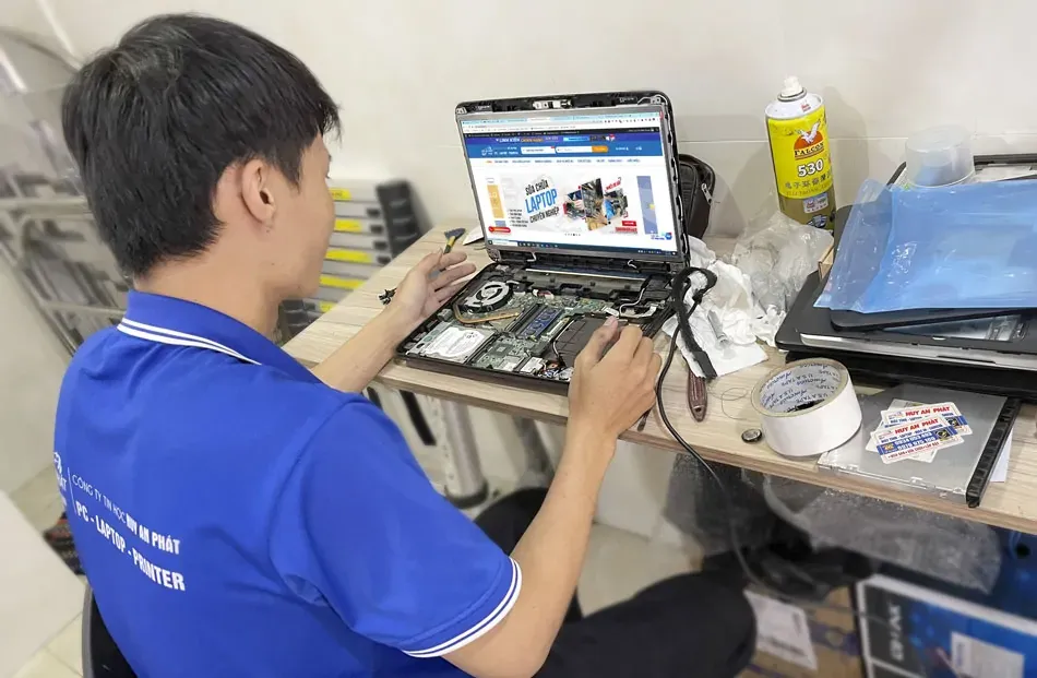 Nhân viên kỹ thuật đang tập trung sửa chữa laptop cho khách hàng tại văn phòng