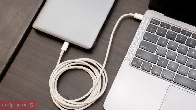 Người dùng sử dụng bộ sạc dự phòng cho laptop để làm việc tại quán cà phê