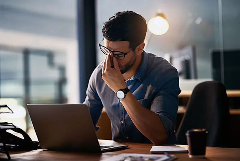 Hình ảnh minh họa một người phụ nữ đeo kính đang nhỏ thuốc nhỏ mắt khi làm việc với máy tính